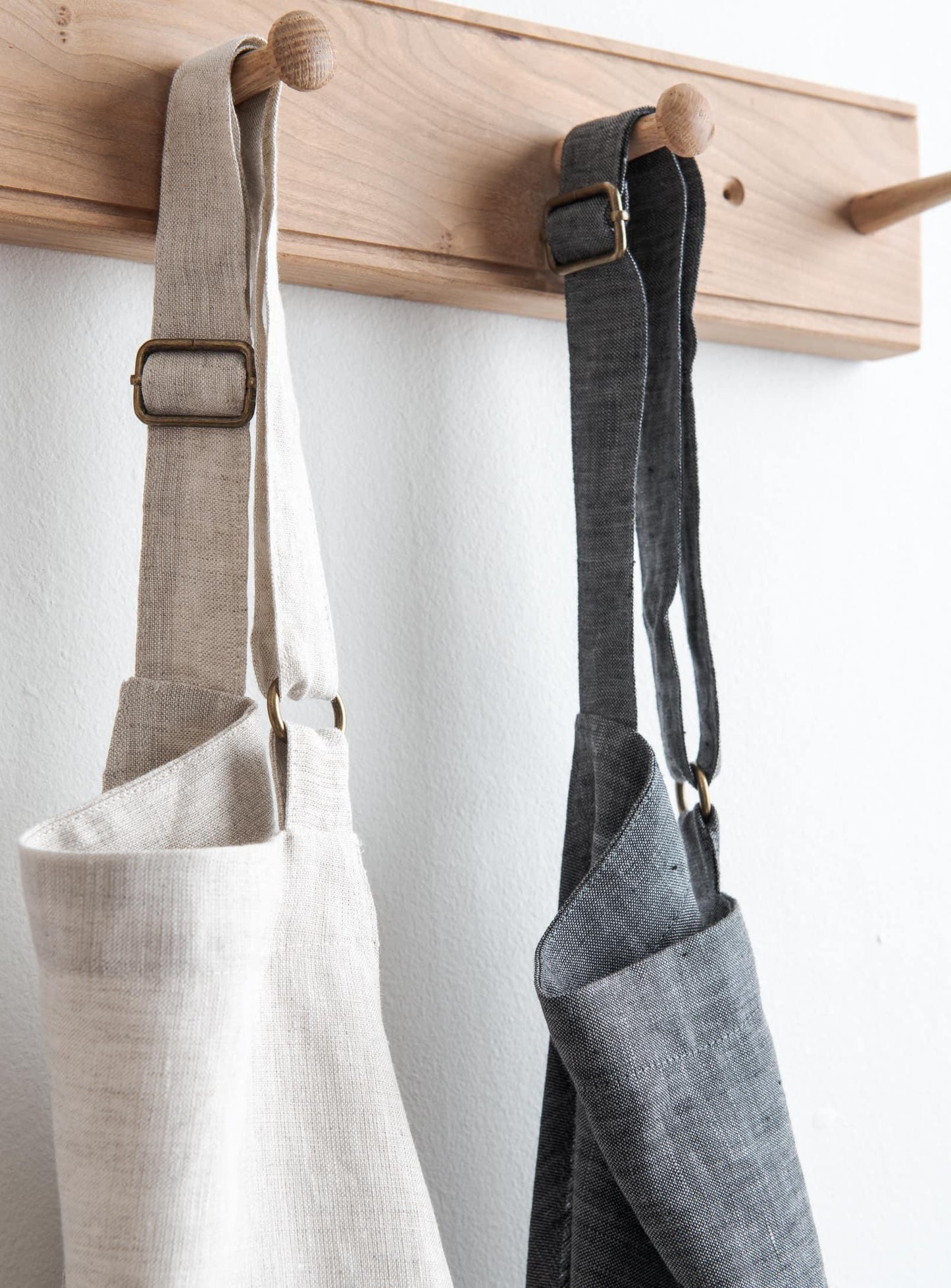 detailed view of two kitchen aprons hanging on a wooden peg rail