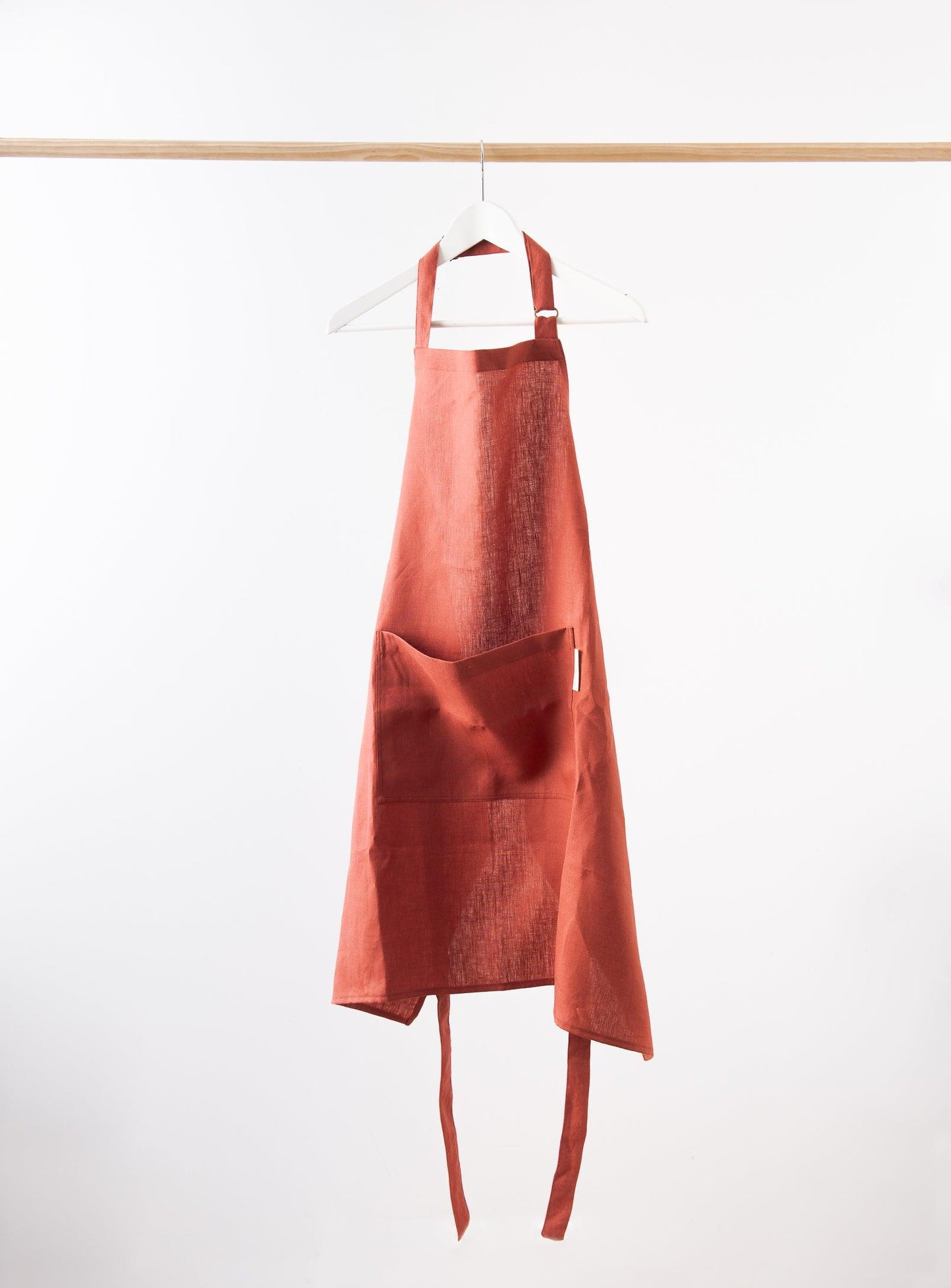 a red apron hung on a wooden hanger