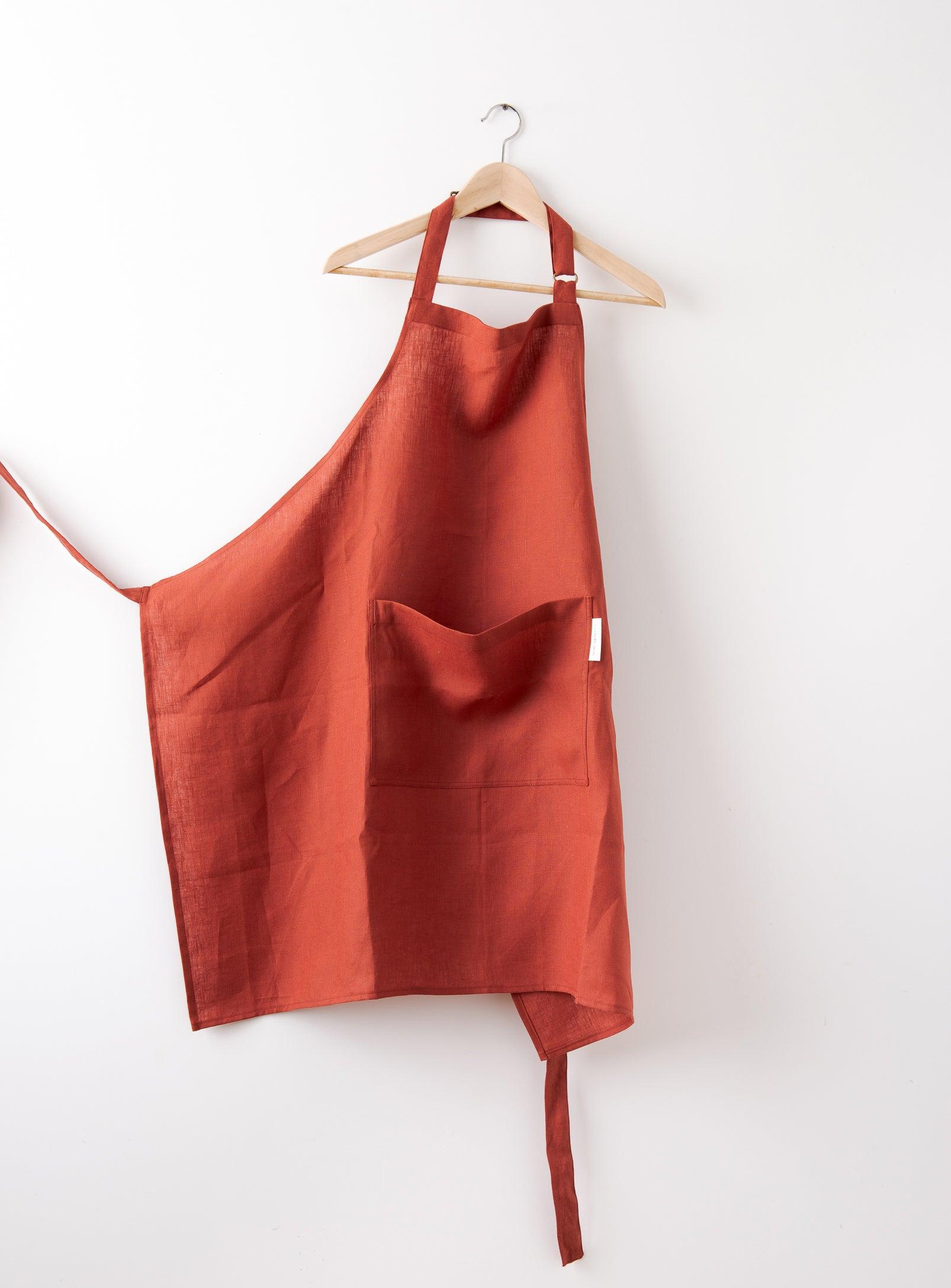 a red apron with pocket in front hung in front of a white wall