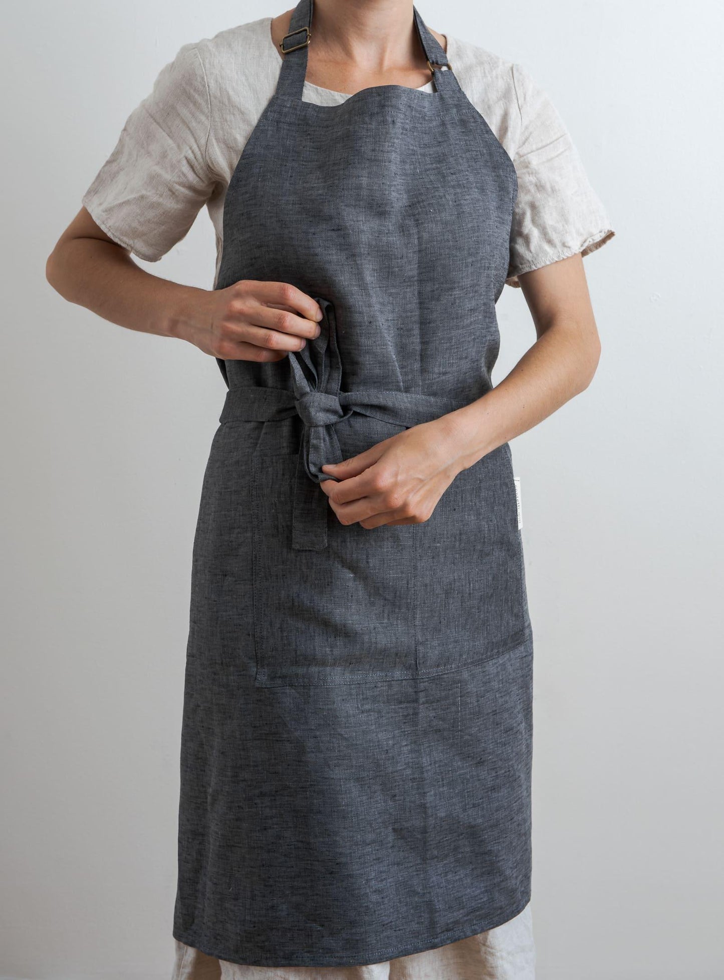 woman tying a grey linen apron