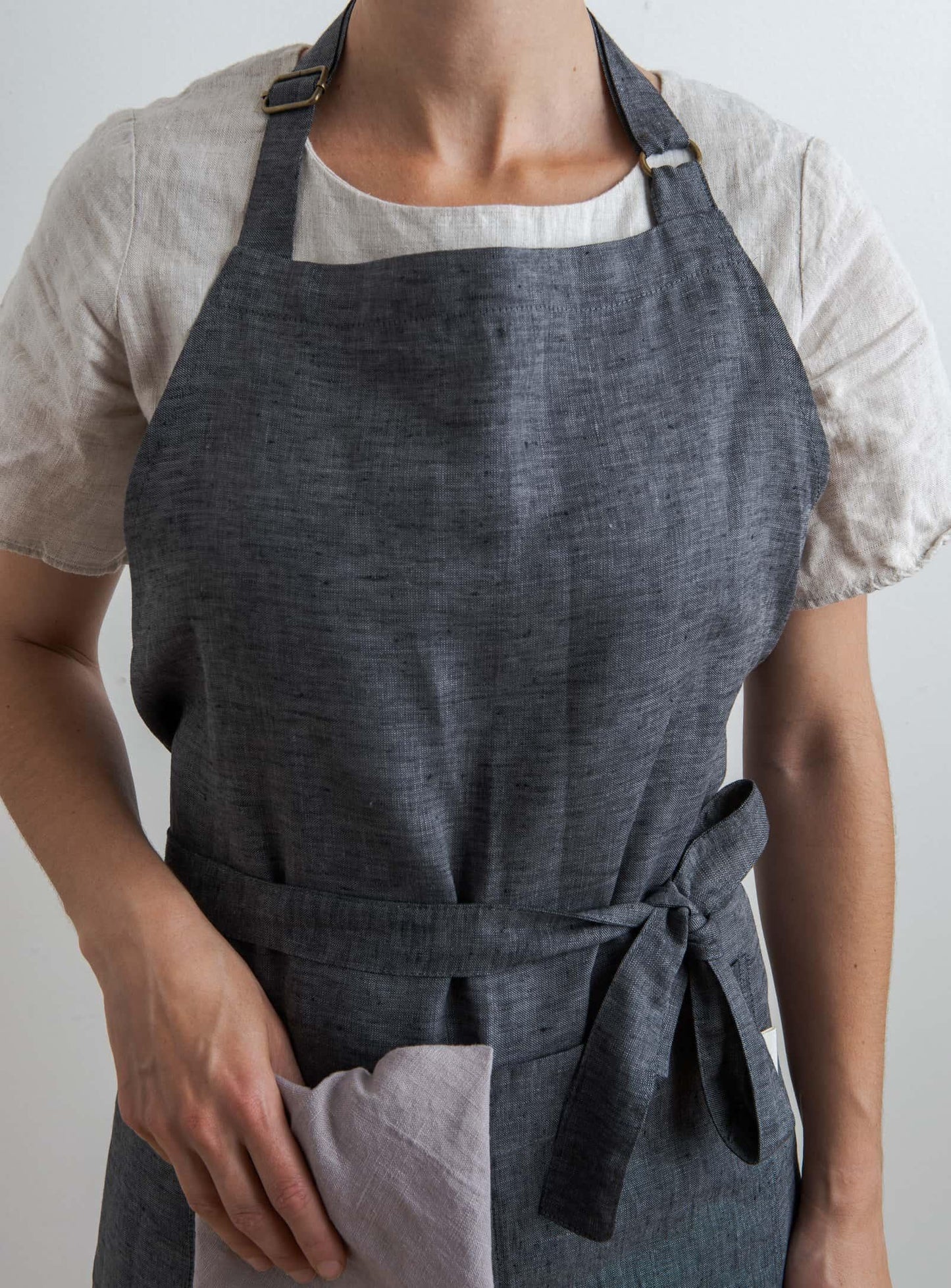 front view of a woman wearing an anthracite coloured kitchen apron holding a napkin