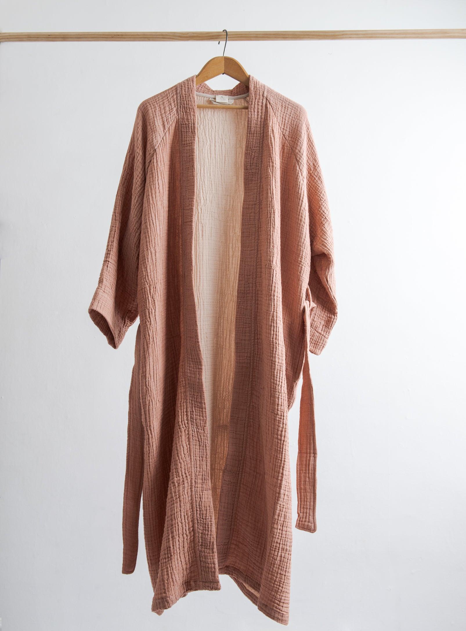 a peachy pink coloured cotton robe hung on a rod