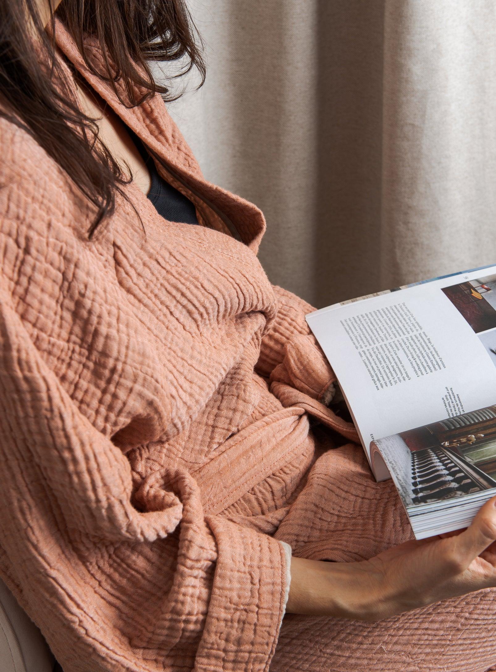 woman sitting in a pink loungewear reading milk magazine