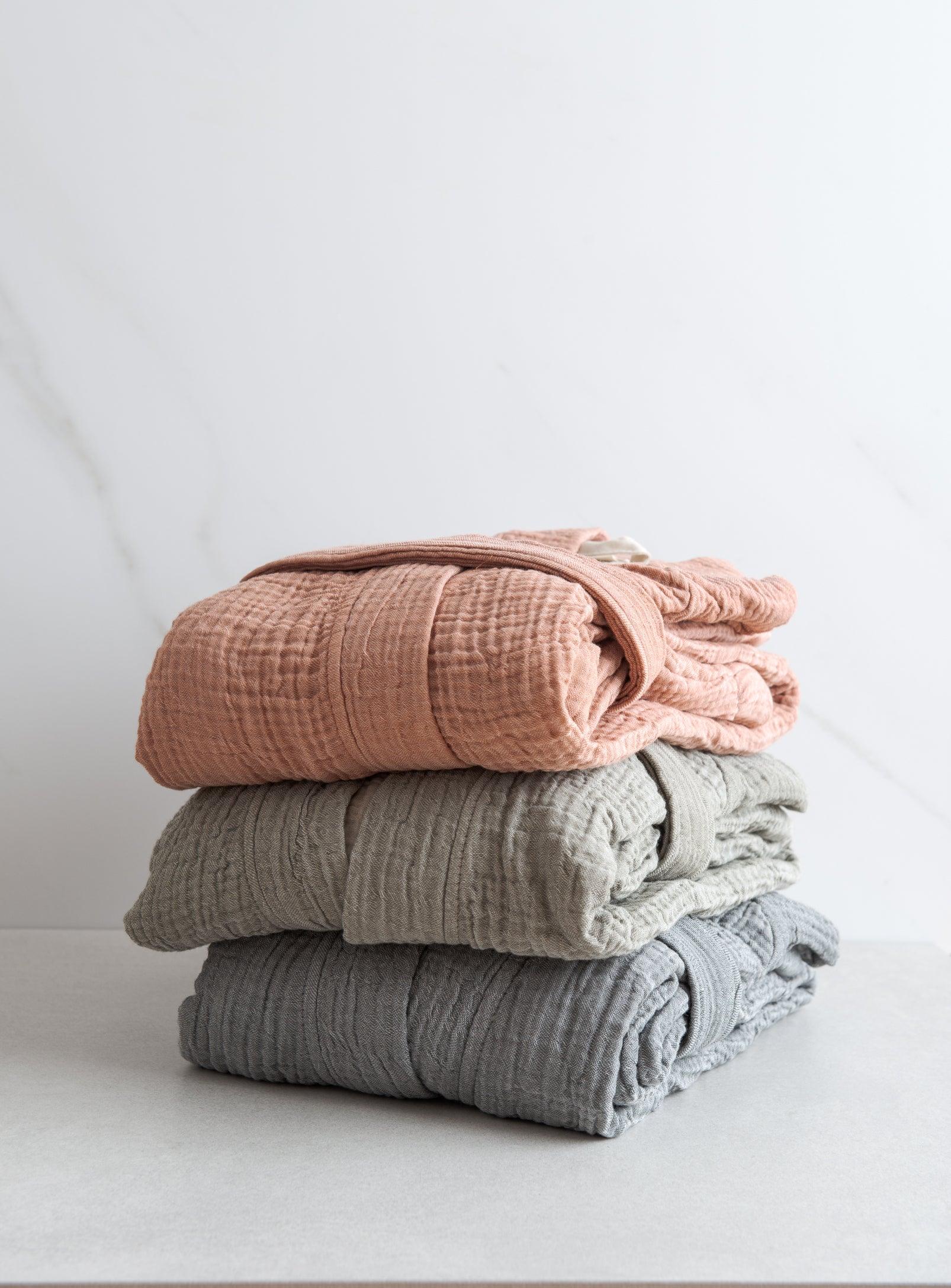 a pile of pink, green and grey muslin bathrobes