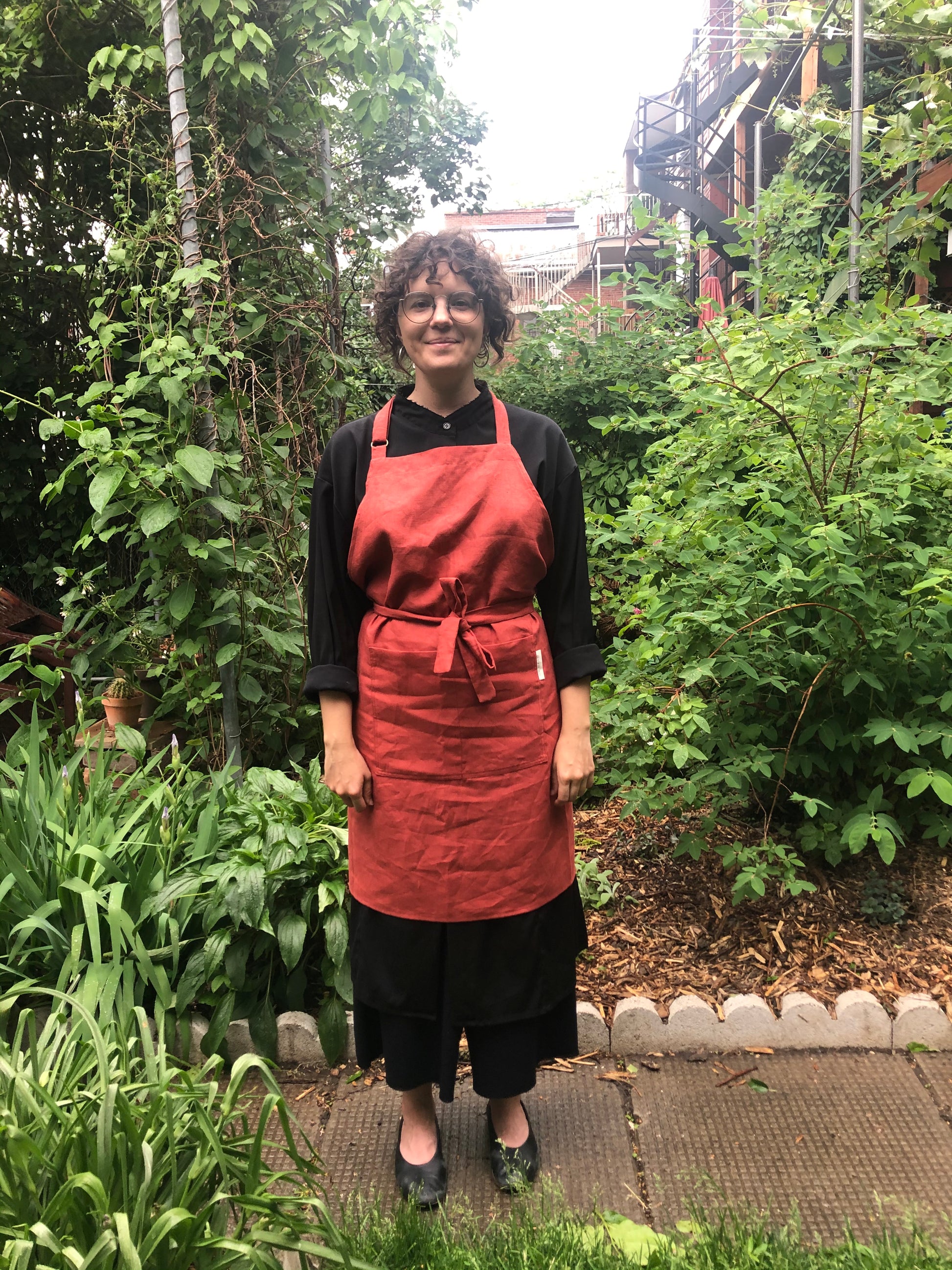woman wearing a red apron standing in a garden