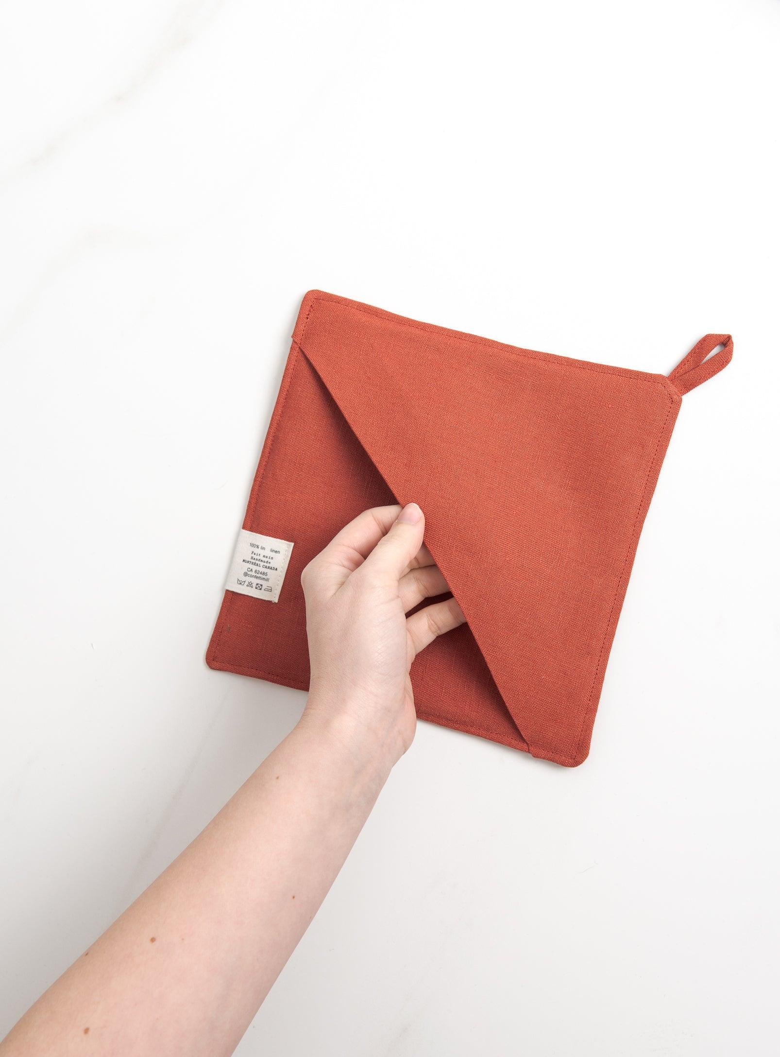 a hand showing the pocket of red pot holder